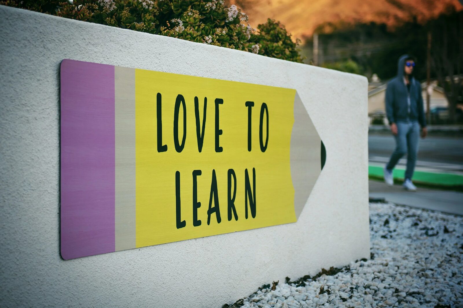 A painted pencil sign reading 'Love to Learn' mounted on a wall